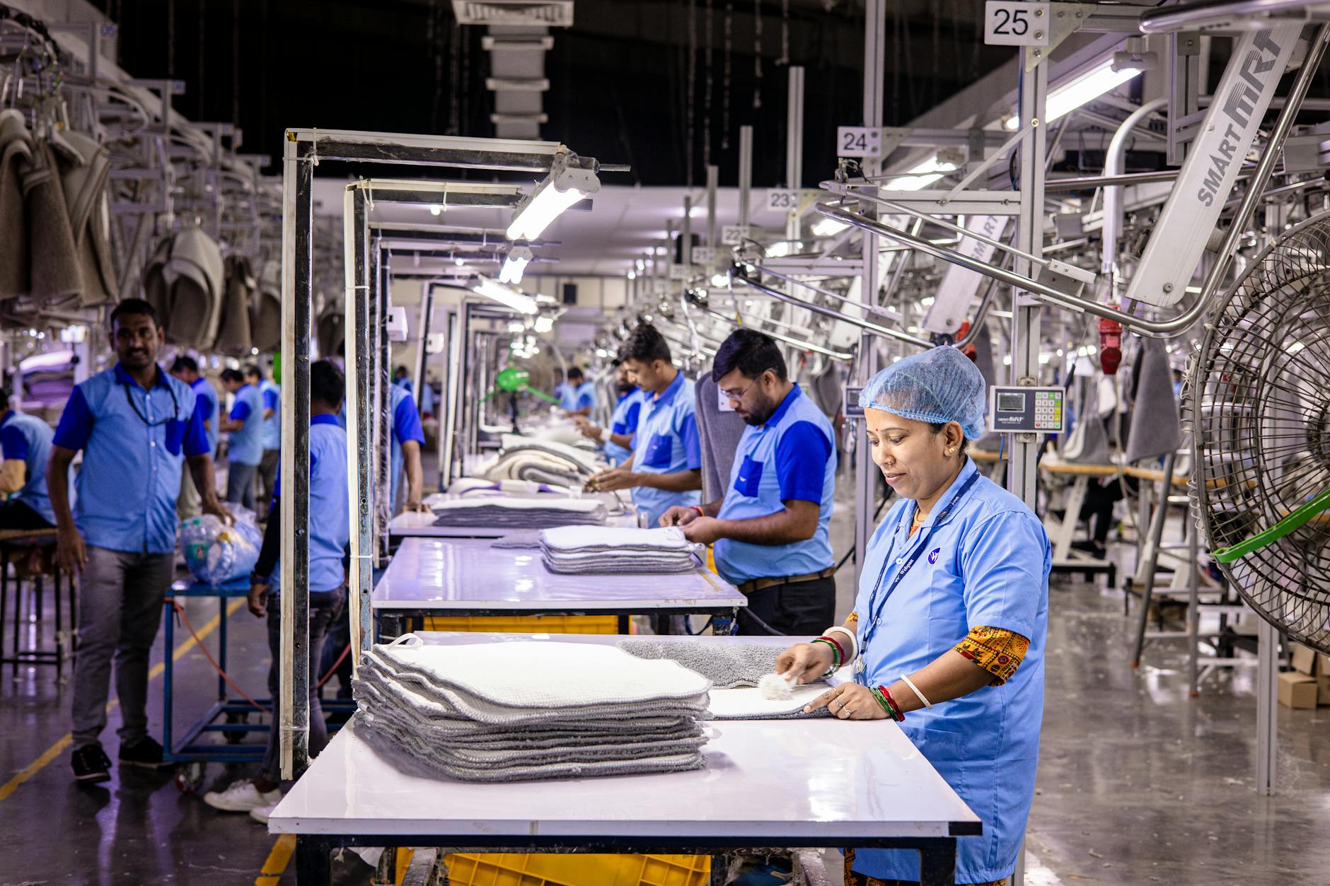 Pracownicy szwalni kontrolują jakość odzieży przy taśmie produkcyjnej