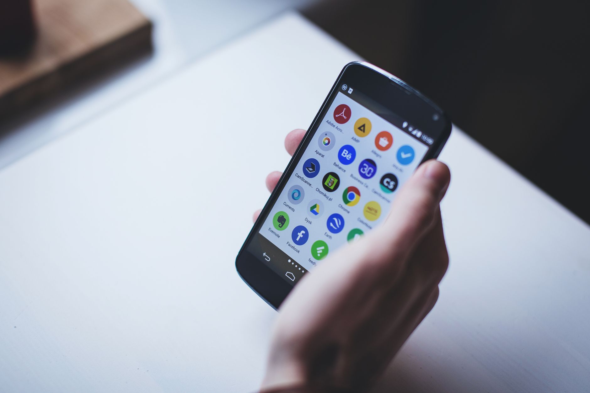 Dłoń trzymająca smartfon z ikonami różnych aplikacji na ekranie