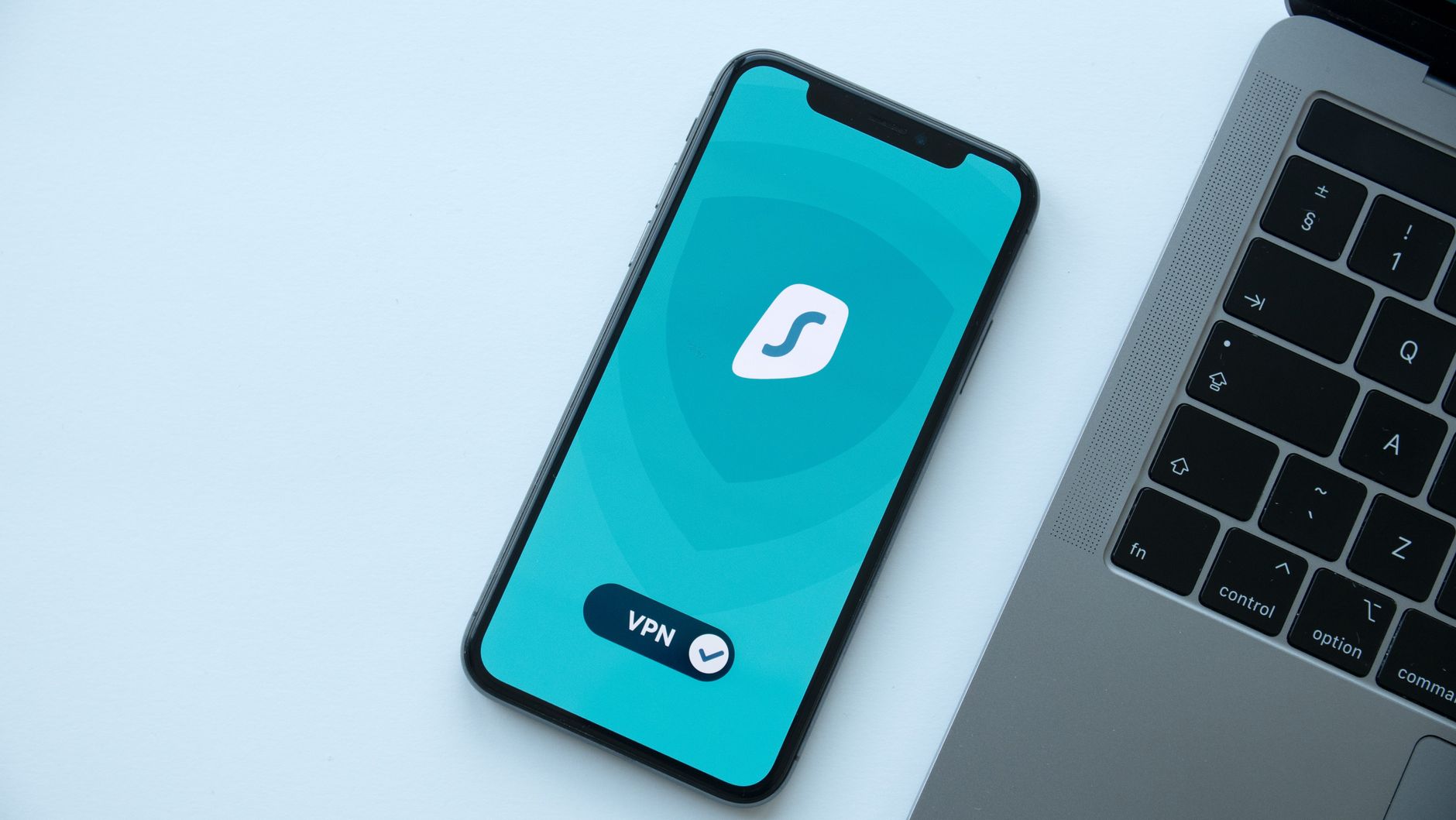 Smartfon z uruchomioną aplikacją VPN obok laptopa na biurku