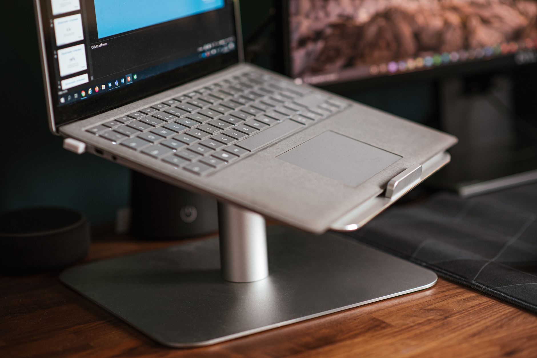 Laptop na podstawce obok monitora na biurku w nowoczesnym biurze