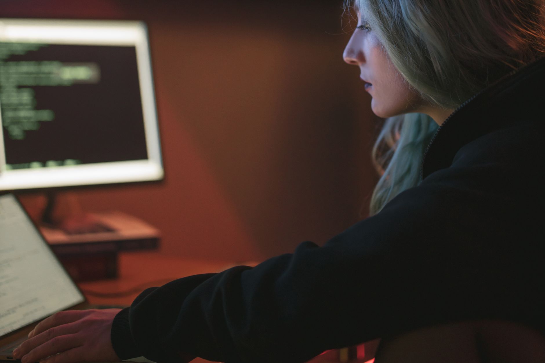 Programistka pracuje nocą przy laptopie z kodem na ekranie
